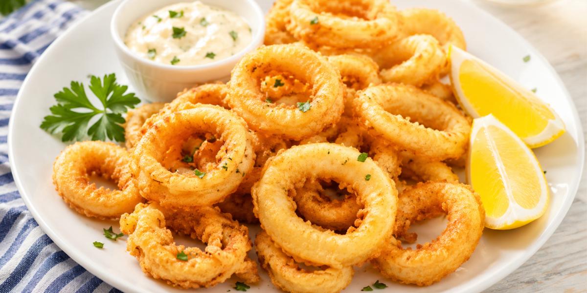 Anillas rebozadas crujientes con limón y salsa en plato blanco