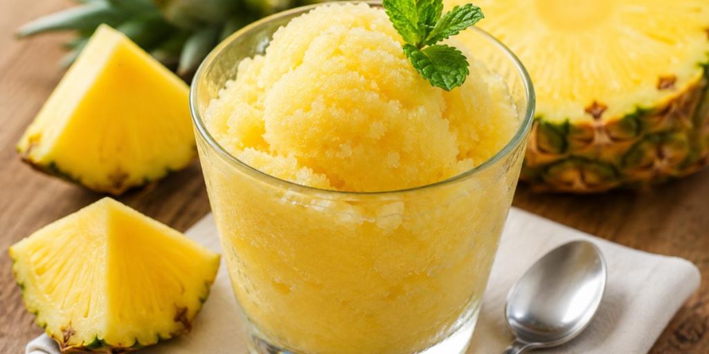 Sorbete de piña servido en vaso con hojas de menta