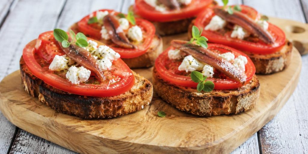 Tostas de pan de leña con tomate fresco, anchoas y mozzarella