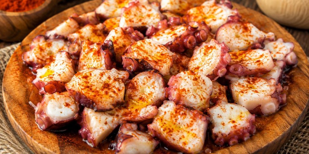 Pulpo á feira servido en plato de madera con pimentón