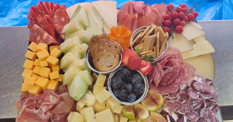 Tabla de embutidos con fruta variada y presentación colorida